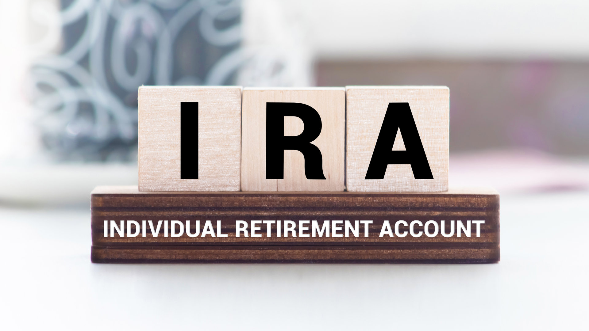 IRA individual retirement account word on wood cube block with blue background.
